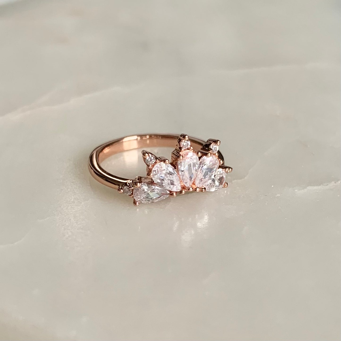 The Magic Ring is an ultimate crown ring in 18K rose gold Vermeil. It is embellished with five sparkling cubic zirconia crystals on a glistening band. The ring gives you an elegant look and is perfect for everyday wear.