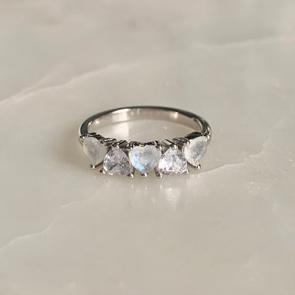 Mila is a stunning five-stone ring with a glistening band. The three heart shaped moonstones and two sparkling cubic zirconia crystals are held in a prong setting and arranged in an alternating pattern.