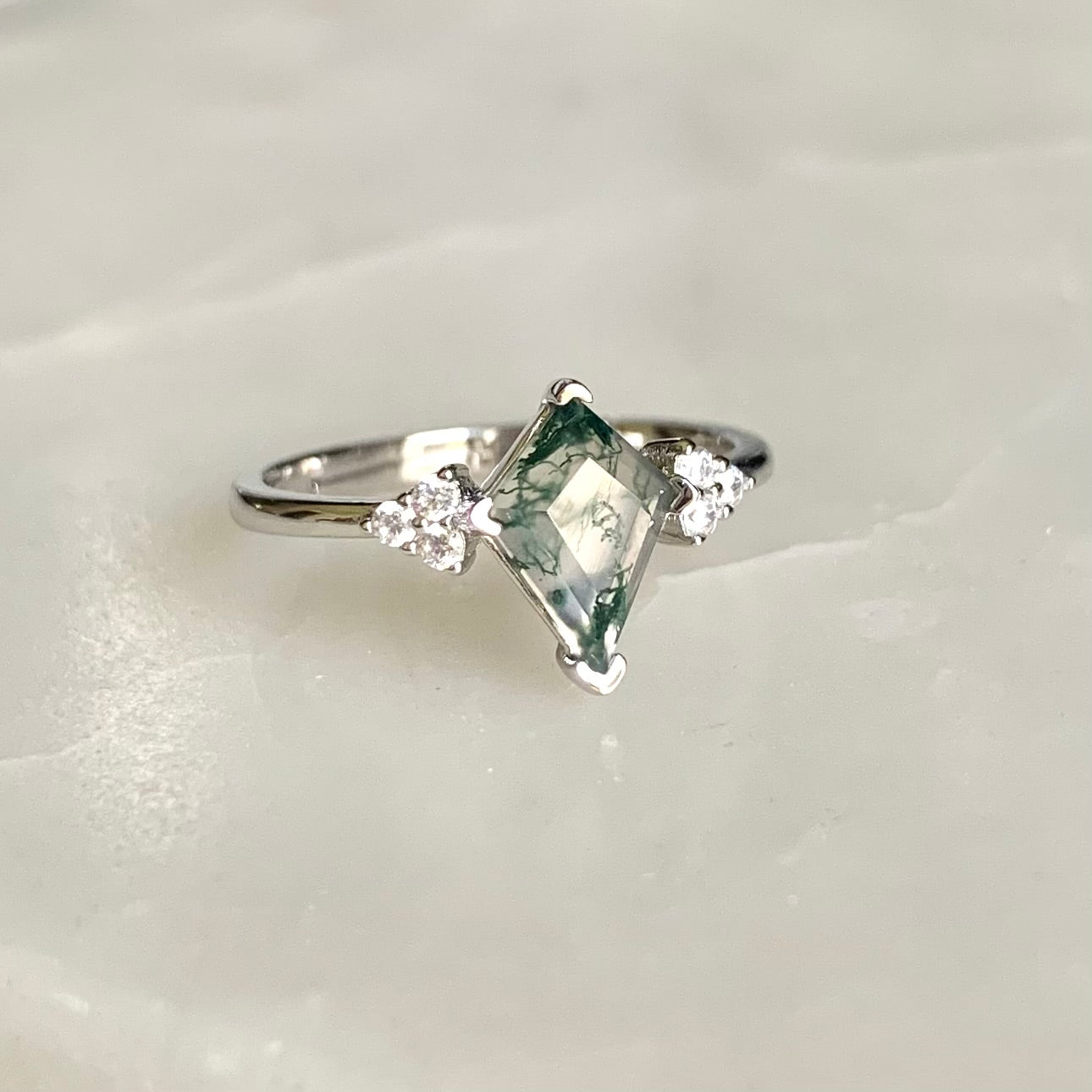 The Evelyn Ring features a unique kite-shaped Moss Agate that is sitting in the centre on a glistening rhodium plated band, accompanied by the sparkled cubic zirconia crystals on both sides. Evelyn is absolutely a unique ring for that one-of-a-kind someone.