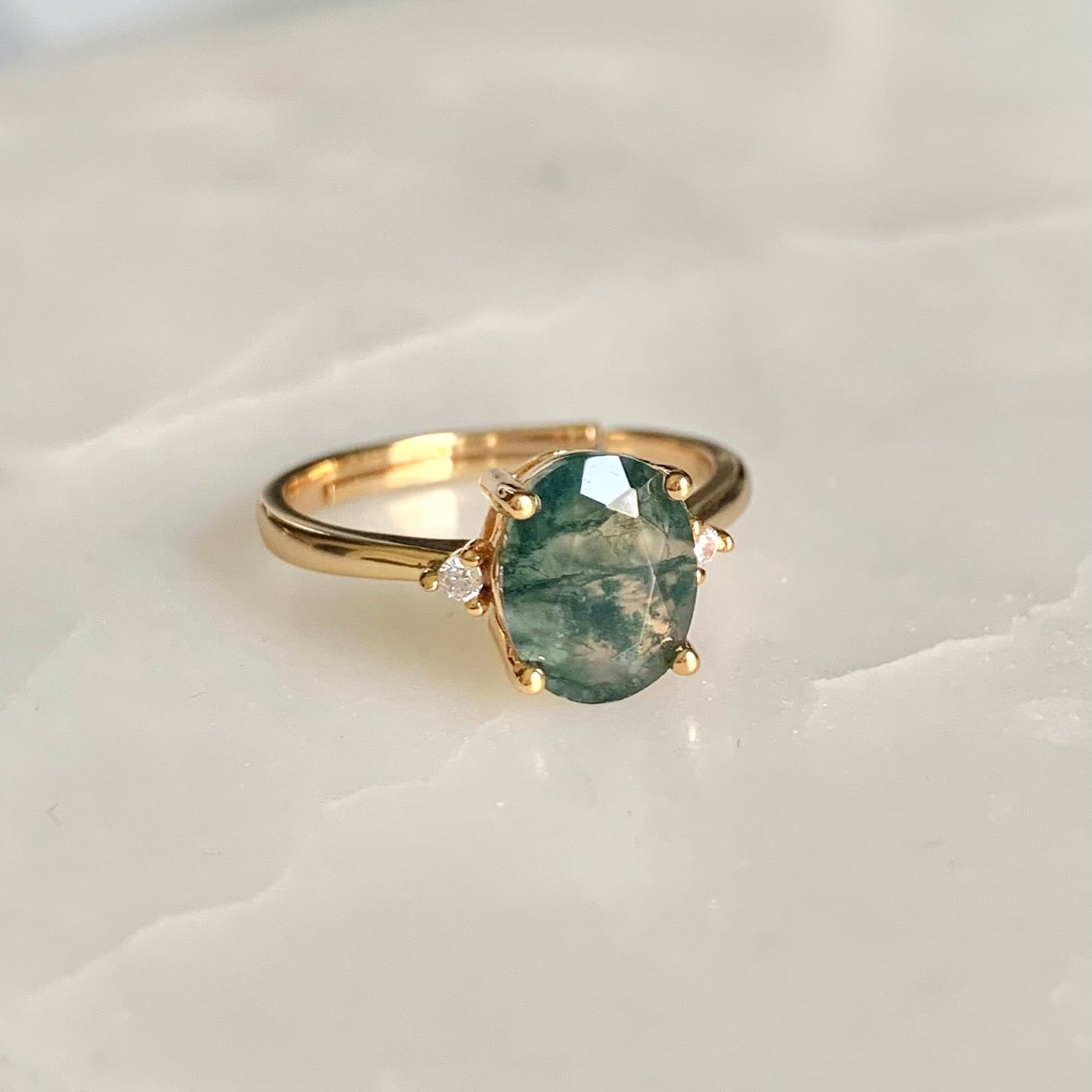 A classic and vintage design gemstone ring. Helena features an oval moss agate stone sits secured in a four prongs setting, embellished with two high quality cubic zirconia crystals accent on each side of the centre gem.