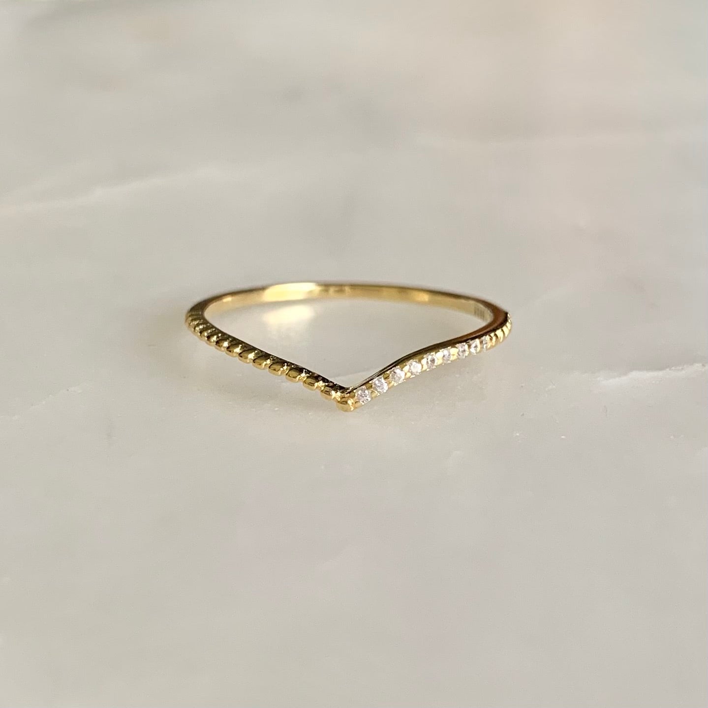 Julianna is a V-shaped stacking ring. If you look at it closer, there is a row of cubic zirconia crystals sit on one side of the band. This dainty and delicate style is so well on pairing with any statement and stacking rings. 