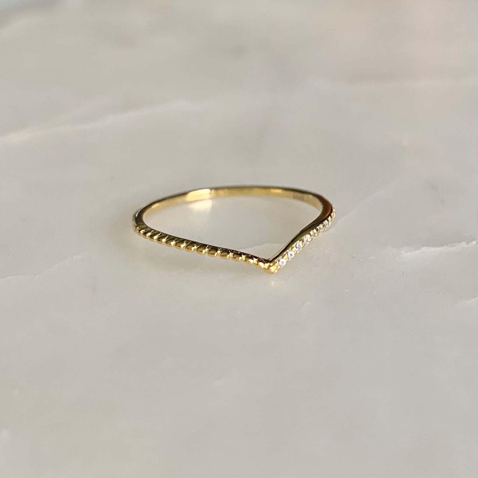 Julianna is a V-shaped stacking ring. If you look at it closer, there is a row of cubic zirconia crystals sit on one side of the band. This dainty and delicate style is so well on pairing with any statement and stacking rings. 