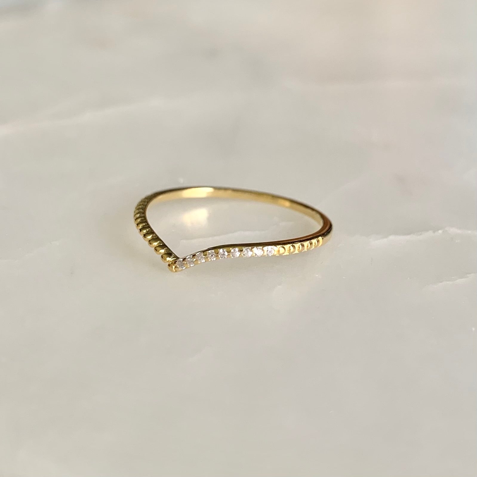 Julianna is a V-shaped stacking ring. If you look at it closer, there is a row of cubic zirconia crystals sit on one side of the band. This dainty and delicate style is so well on pairing with any statement and stacking rings. 