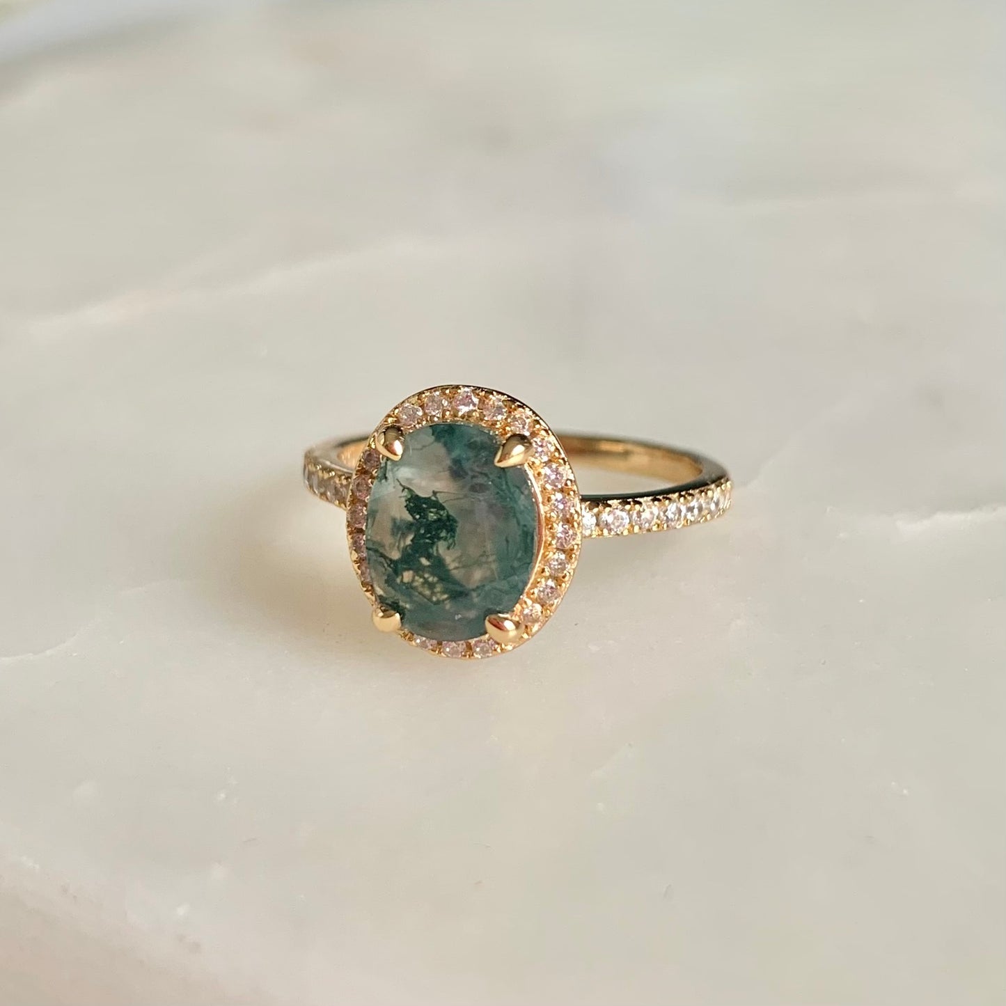 Crafted with exquisite detail, this Fern Moss Agate Ring is perfect for creating an air of sophistication. The halo-style design is adorned with shimmering cubic zirconia set in a feminine, floral pattern. Capture elegant style with this unique piece.