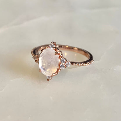 14K rose gold vermeil Queenie Moonstone Ring.  It has an oval moonstone set in a classic four-prong setting, embellished with tiny round beads and sparkling cubic zirconia crystals which highlights the femininity of its design. It is a truly meaningful piece of wearable art. 